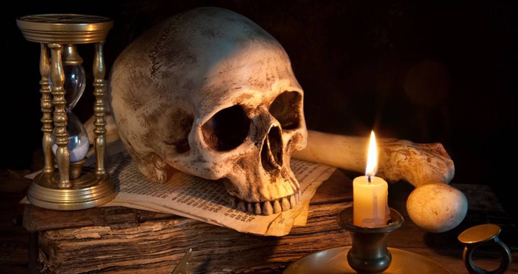 Vintage skull on antique book with candle and hourglass