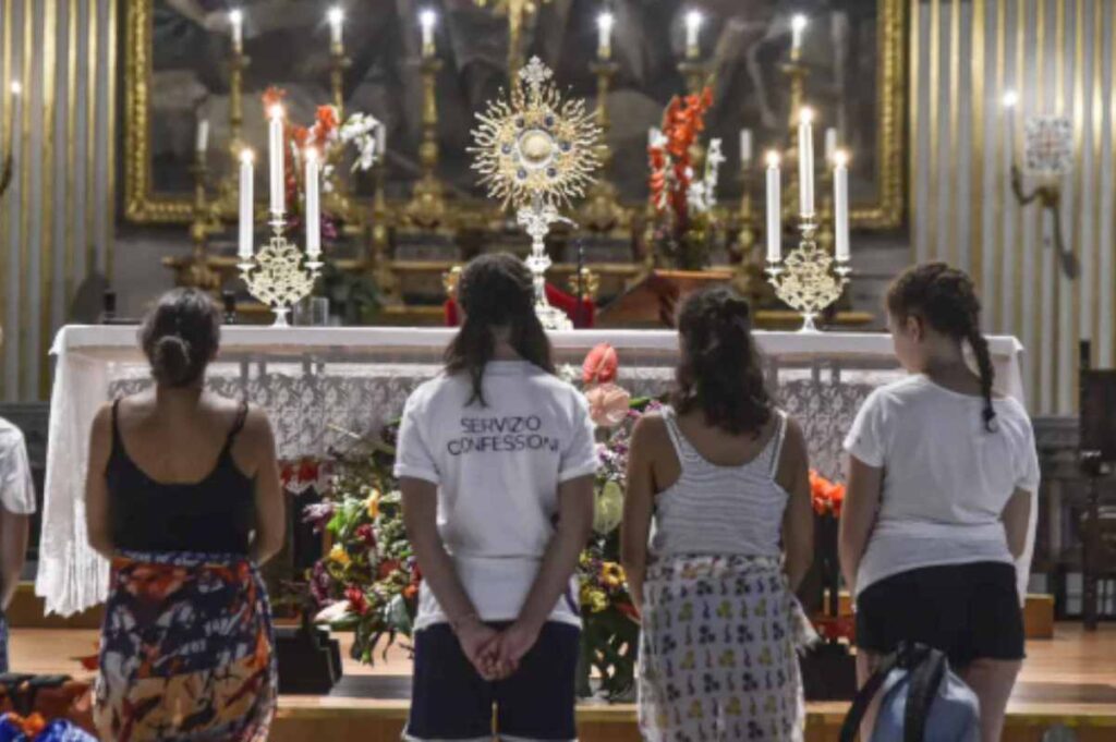 giovani in ginocchio davanti al santissimo sacramento