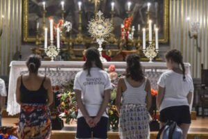 giovani in ginocchio davanti al santissimo sacramento