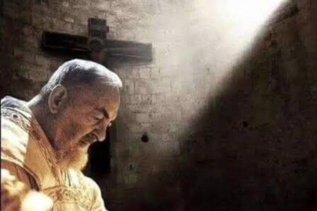 padre pio con alle spalle una luce e una croce