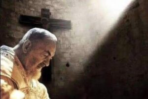 padre pio con alle spalle una luce e una croce