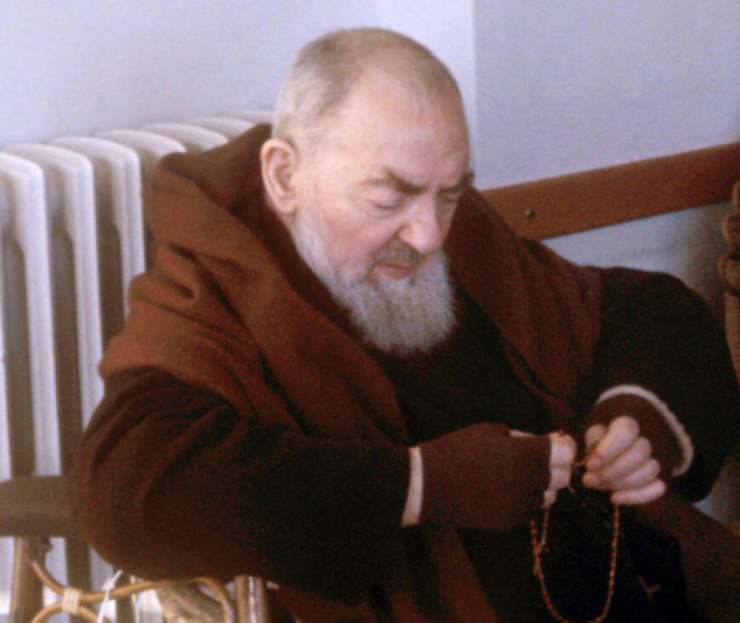 padre pio seduto recita rosario