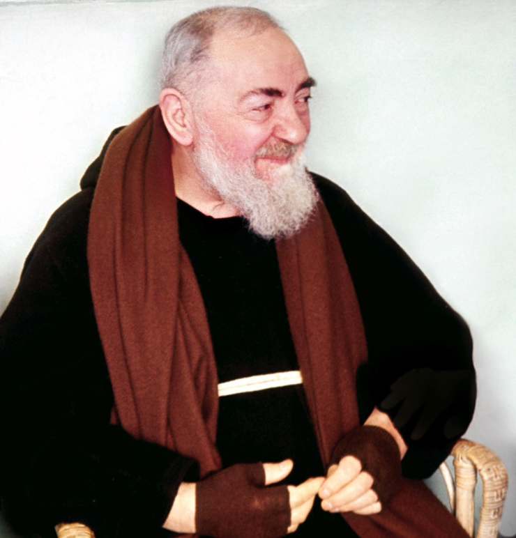 padre pio seduto che sorride