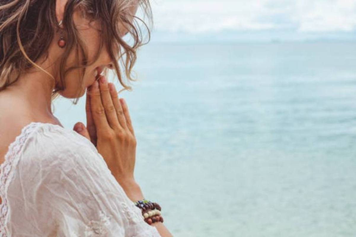 donna che prega con sfondo mare